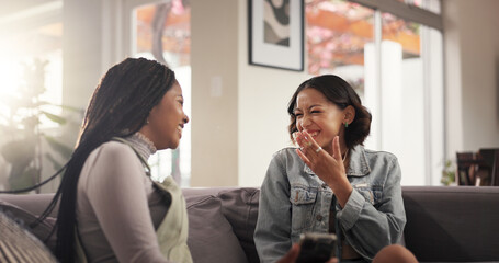 Fototapeta premium Laughing, friends and women with smartphone, home and bonding with gossip on social media and happiness. House, smile and people with mobile for funny news on post, reunion or together in living room