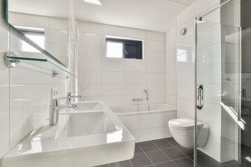 A spacious, bright bathroom featuring sleek white tiles, a contemporary bathtub, and glass shower. Ideal for showcasing modern interior aesthetics.
