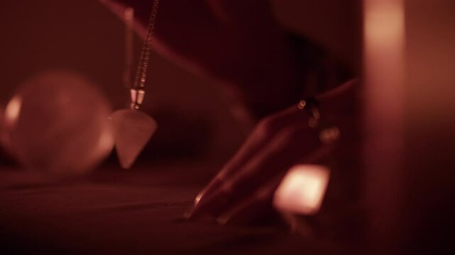 Using a pendulum for divination at candlelit spiritual table