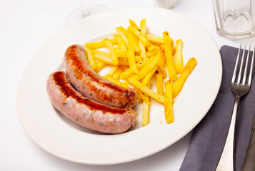 Close up of tasty fried pork sausages with french fries, served on plate