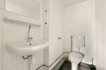 A clean and minimalistic bathroom featuring a sink, toilet, and tiled walls, emphasizing simplicity...