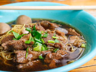 Braised beef noodle soup set on wooden table.