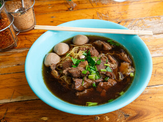 Braised beef noodle soup set on wooden table.