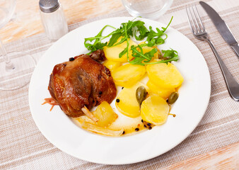 Traditional French dish duck confit with roasted potatoes on table.