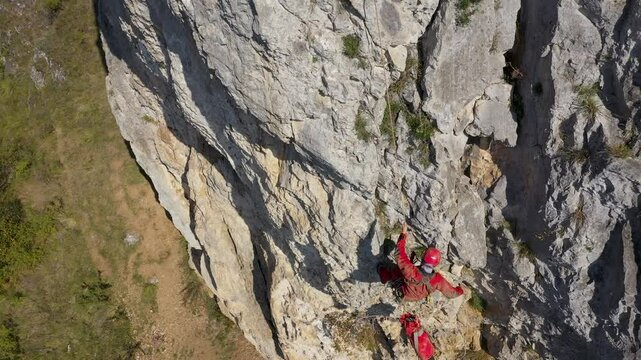  Aerial view of mountain rescuer rappelling on a rocky wall hanging on a rope