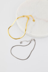 Gold and silver bracelets on circular white marble tray. Jewellery 