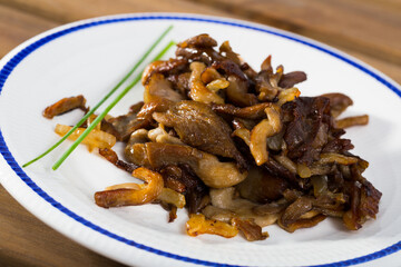 Close-up of tasty cooked fried oyster mushrooms at plate at table