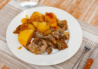 Delicious dinner of spicy braised potatoes with pieces of rabbit on plate..