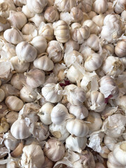 A pile of white garlic bulbs with some of them broken