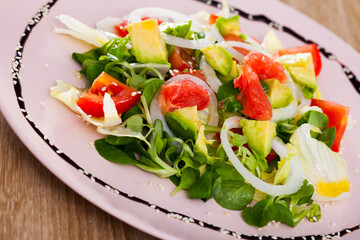 Fresh colorful salad with ripe avocado, tomatoes, grapefruit and green corn salad..