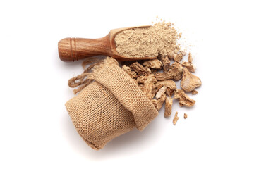 A scoop of organic dried Ginger Root powder, along with whole Ginger Root (Zingiber officinale) or sonth, spilled out from a jute bag. Isolated on a white background.