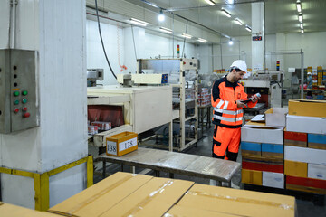 Male worker inspecting canned products in a seafood factory packaging area