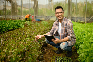 Fototapeta premium Agricultural entrepreneur using digital tablet in a greenhouse. Concept of agri business innovation