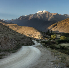 Winding road through the scenic landscape of rural Kyrgyzstan Barskoon valley mountains during early morning light