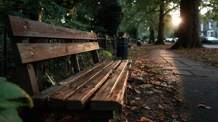 Fototapeta premium Peaceful empty wooden bench on autumn park path at sunset