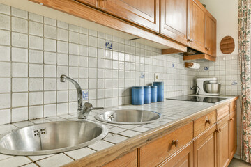 A warm and inviting kitchen featuring wooden cabinets, tiled countertops, and a simple design. Ideal for showcasing home aesthetics and functionality.