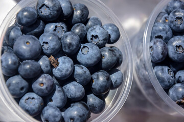 Blue blueberry in large plastic cups. Sale of fresh ripe juicy berries, street trade. Healthy and tasty food. Close-up. Top view.
