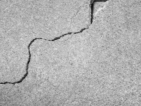 Crack on old plastering wall. Big long curve winding diagonal ascending, Fracture, Fissure, Split, Break, Cleft. Copy space. Black and white photo. Selective focus.