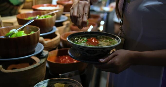 squeeze lime into a bowl of soup warm bowl of Vietnamese chicken noodle soup with lime and fresh herbs being garnished