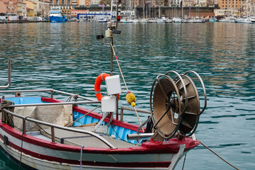 Obraz premium A small fishing boat is anchored in a serene harbor, surrounded by colorful buildings and larger yachts.