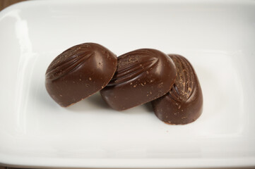 stack of chocolates, on a white square plate, wooden background,