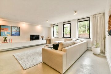 A stylish and contemporary living room featuring a cozy sofa, a sleek TV unit, and large windows that let in plenty of natural light, creating an inviting atmosphere.