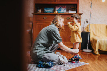 A caring mother assists her toddler to get dressed in a cozy and family-oriented house, emphasizing bonding.