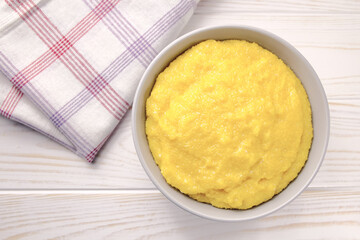 Delicious corn porridge in a bowl on a white wooden table.