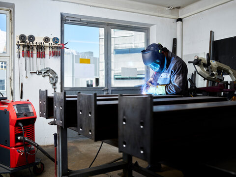 Welding technician performing welding work with protective equipment in his workshop