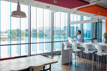 Businessman working on a laptop in a modern office with a city view