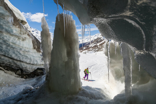 Woman backcountry skier outside entrance to glacier ice cave