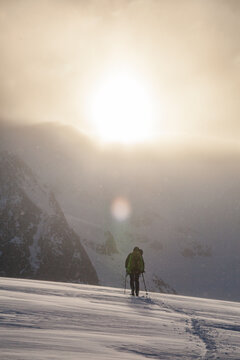 Silhouette of backcountry of skier at sunrise during a snow storm