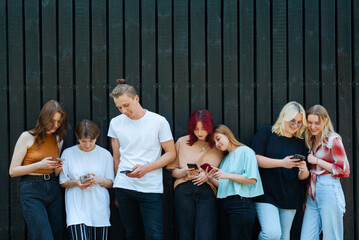 Teenagers standing together using phones outside