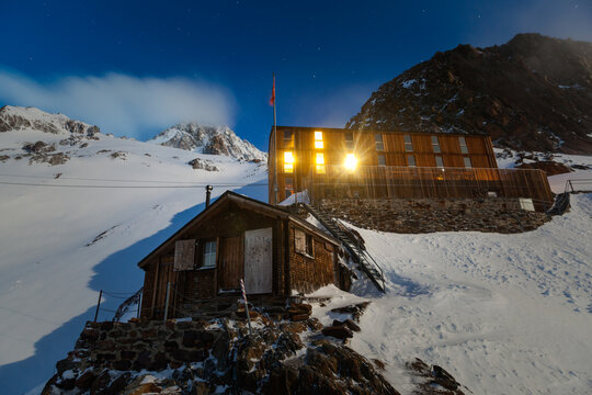 Finsteraarhorn Hut at night on steep slope with snowy mountains