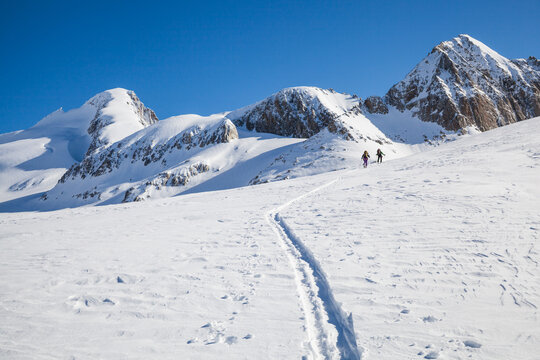 Backcountry skiers on Galmi Glacier below snow-covered mountain peaks