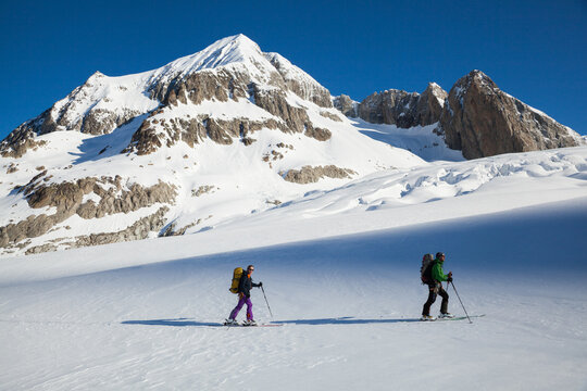 Backcountry skiers on Galmi Glacier below snow-covered mountain peak