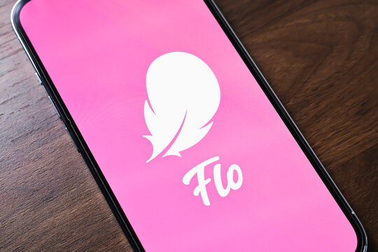 Poznan, Poland - March 26, 2025: Flo period tracking app logo displayed on smartphone screen with pink background placed on wooden desk