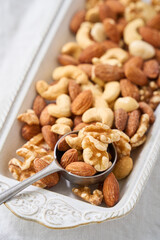 白い器に盛り付けたミックスナッツとスプーン