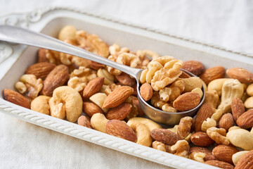 白い器に盛り付けたミックスナッツとスプーン
