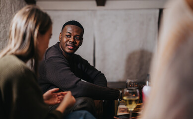 A group of friends talking and sharing moments while enjoying drinks in a dimly lit bar.