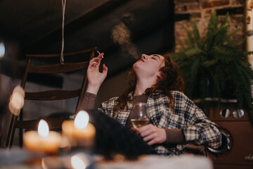 A woman enjoying a serene moment indoors, holding a wine glass and smoking casually. The ambiance...