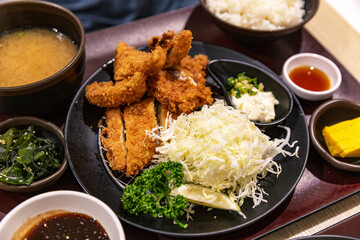 Close-up of Japanese fillet katsu set with crispy pork fillet cutlet and fried shrimp, served with tartar sauce, shredded cabbage, and miso soup