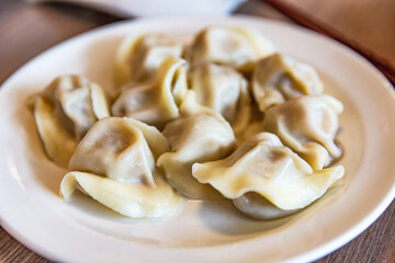 Plate of boiled Chinese dumplings with soft and glossy dough skin, arranged in a circle, filled with meat or vegetable stuffing