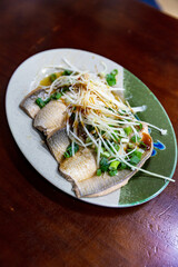 Braised milkfish fillet served cold on a ceramic plate, topped with shredded ginger and scallions, traditional Taiwanese appetizer