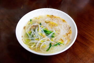 Taiwanese rice noodle soup served in a bowl with light broth, topped with celery and fried shallots, a comforting local classic