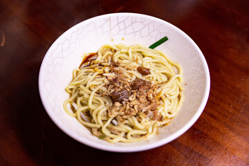 Dry noodles topped with minced pork sauce, chopped scallions, and garlic, traditional Taiwanese lu rou gan ban mian served in white bowl