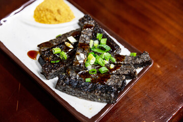 Taiwanese pig blood rice cake sliced and served on a stick, coated in peanut powder and cilantro, traditional street food snack