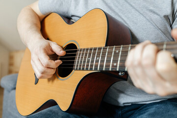 Close-up of a man's hands playing the guitar and strumming chords