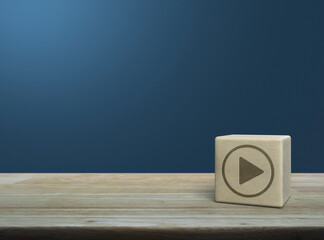Play button icon on wood block cube on wooden table over light blue wall, Business music online concept