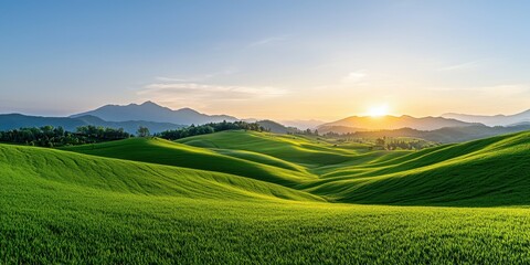 Obraz premium Breathtaking sunset over rolling green hills and mountains in the distance.